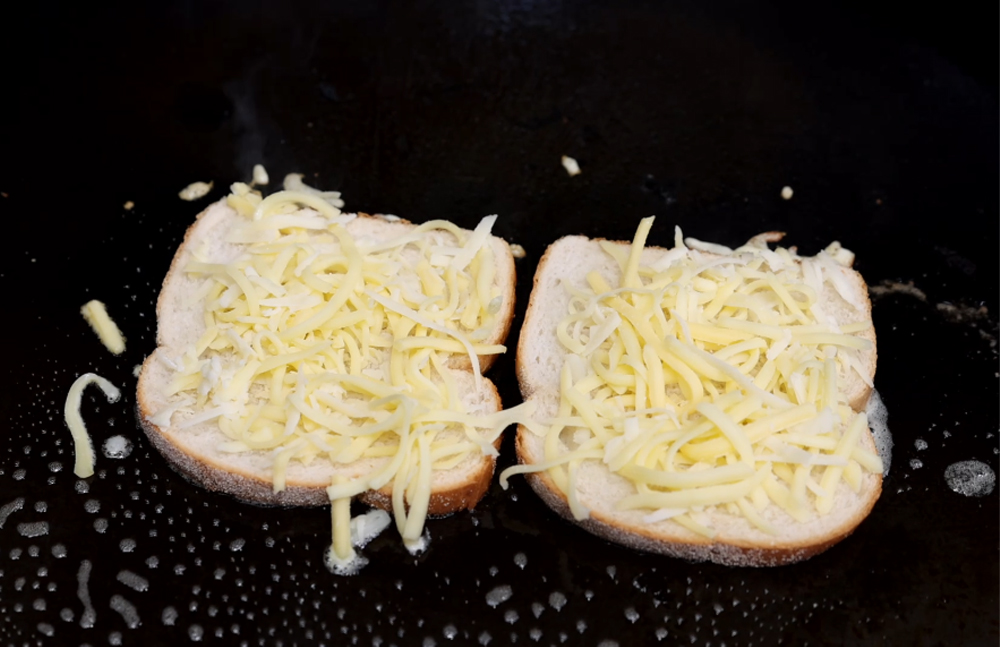This_image_shows_bread_with_cheese_being_placed_on_SNS_plancha_hotplate
