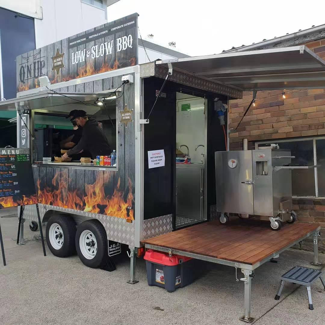 Restaurant and commercial grade gravity fed smoker being used on the back of a kitchen for a catering event. 