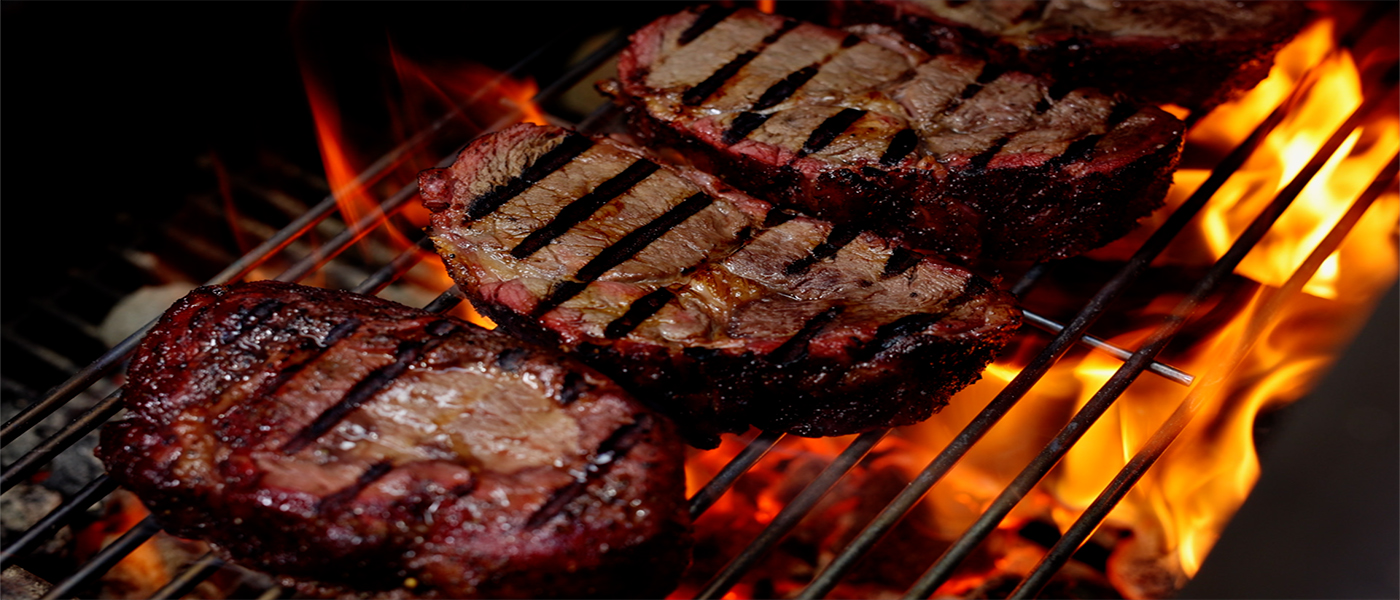This image shows a reverse sear steak on flaming coals offset smoker