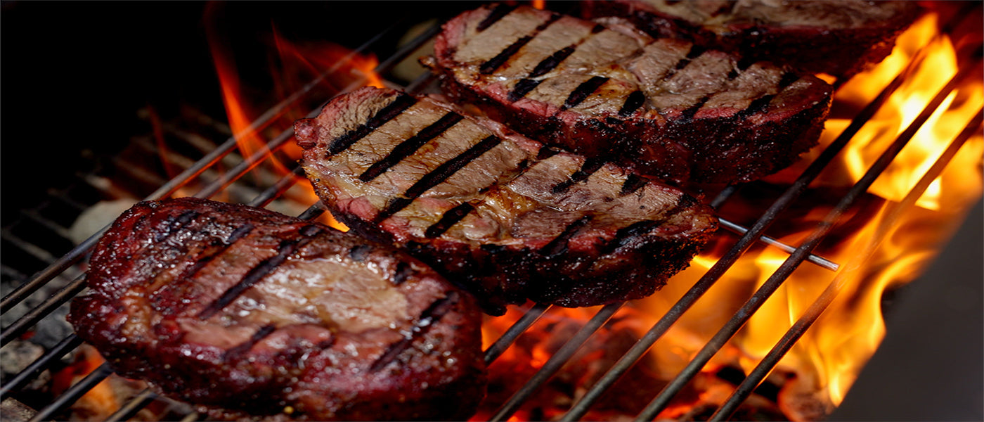 This image shows a reverse sear steak on flaming coals offset smoker