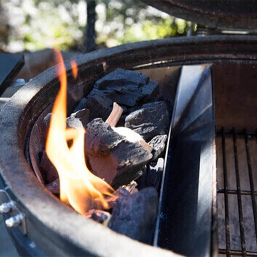 Slow ’N Sear Original Charcoal Basket inside a BBQ grill, filled with burning charcoal for two-zone cooking.