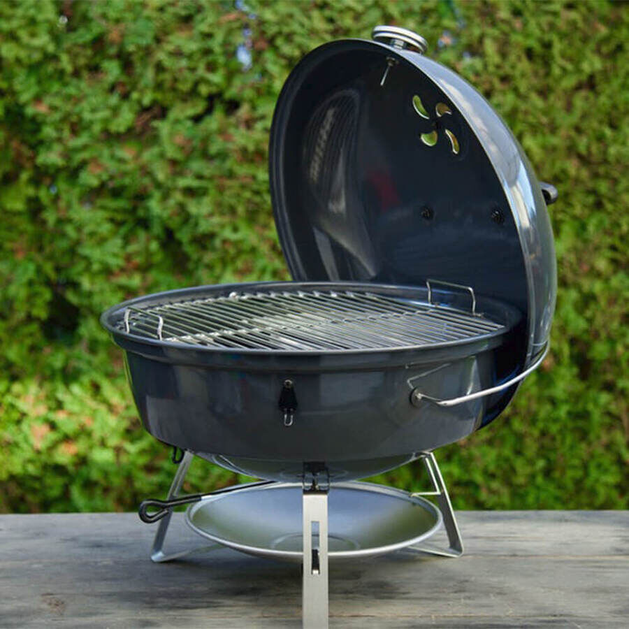 SNS Travel Kettle Grill with lid open, showing cooking grate and compact portable charcoal design, placed on an outdoor table.