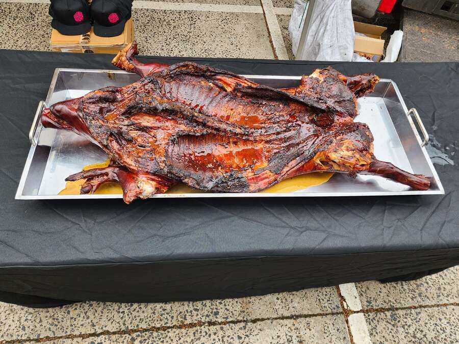 Whole cooked suckling pig displayed on a large stainless steel carving tray