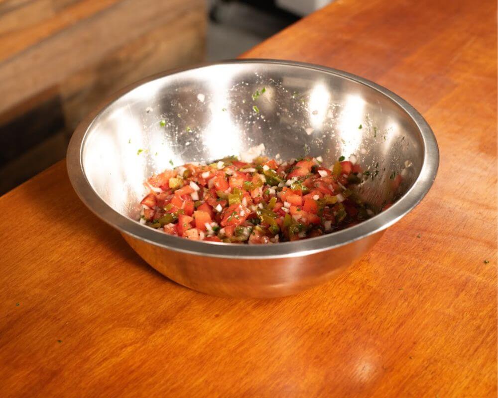 Fresh homemade salsa with chopped tomatoes, jalapeños, onions and coriander prepared as a topping for pulled pork.