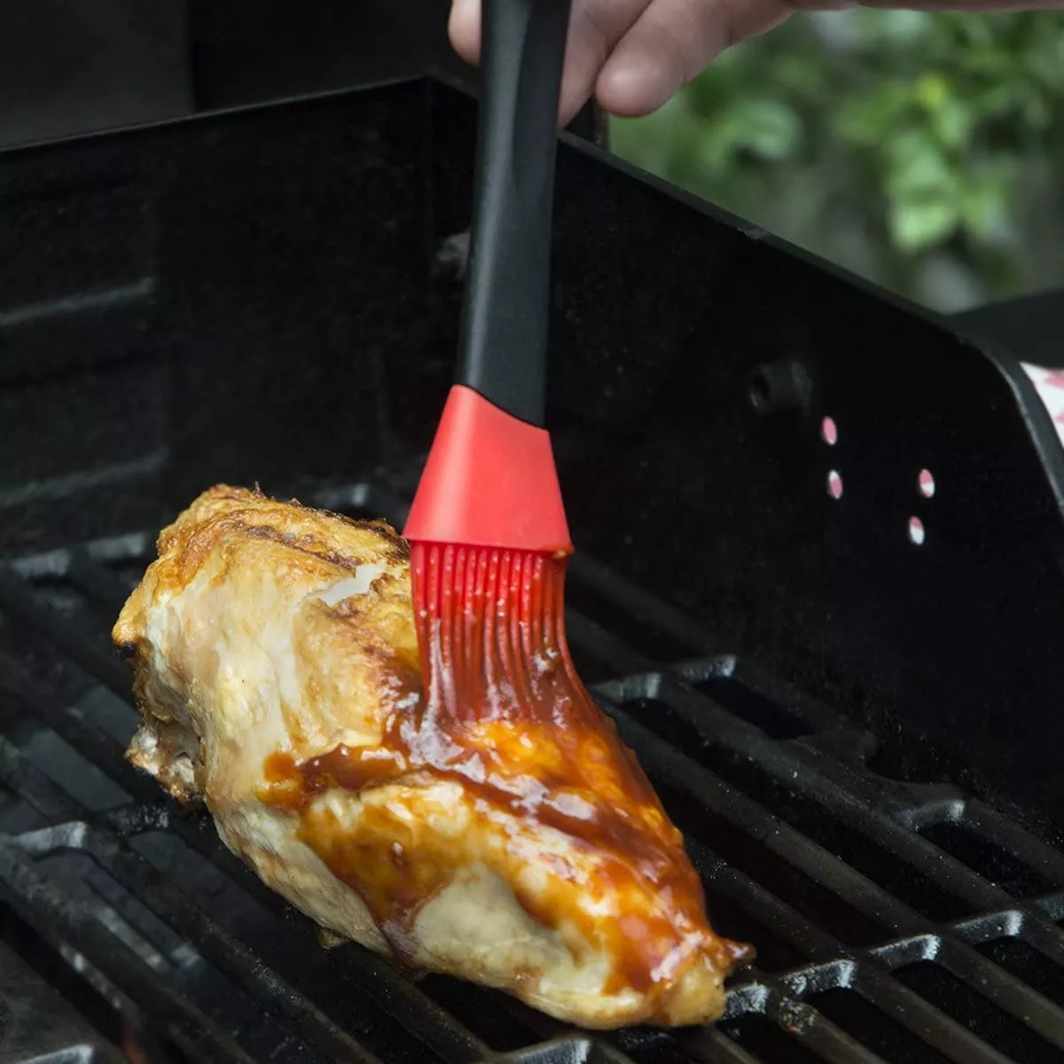 This image show chicken being basted by using the BBQ sauce pot with silicone basting brush. 