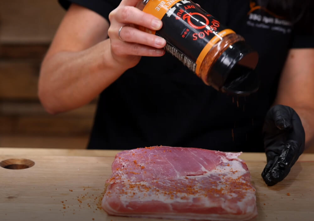 This_image_shows_pork_belly_being_seasoned_with_Kosmos_Q_killer_honey_bee