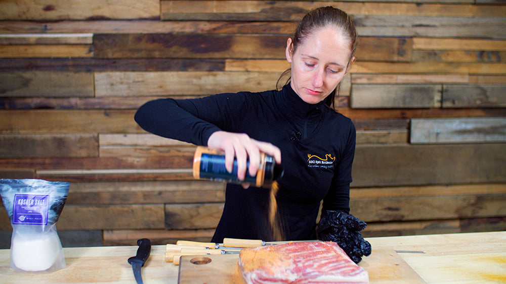 This image shows pork belly being seasoned with Greek Gyros seasoning