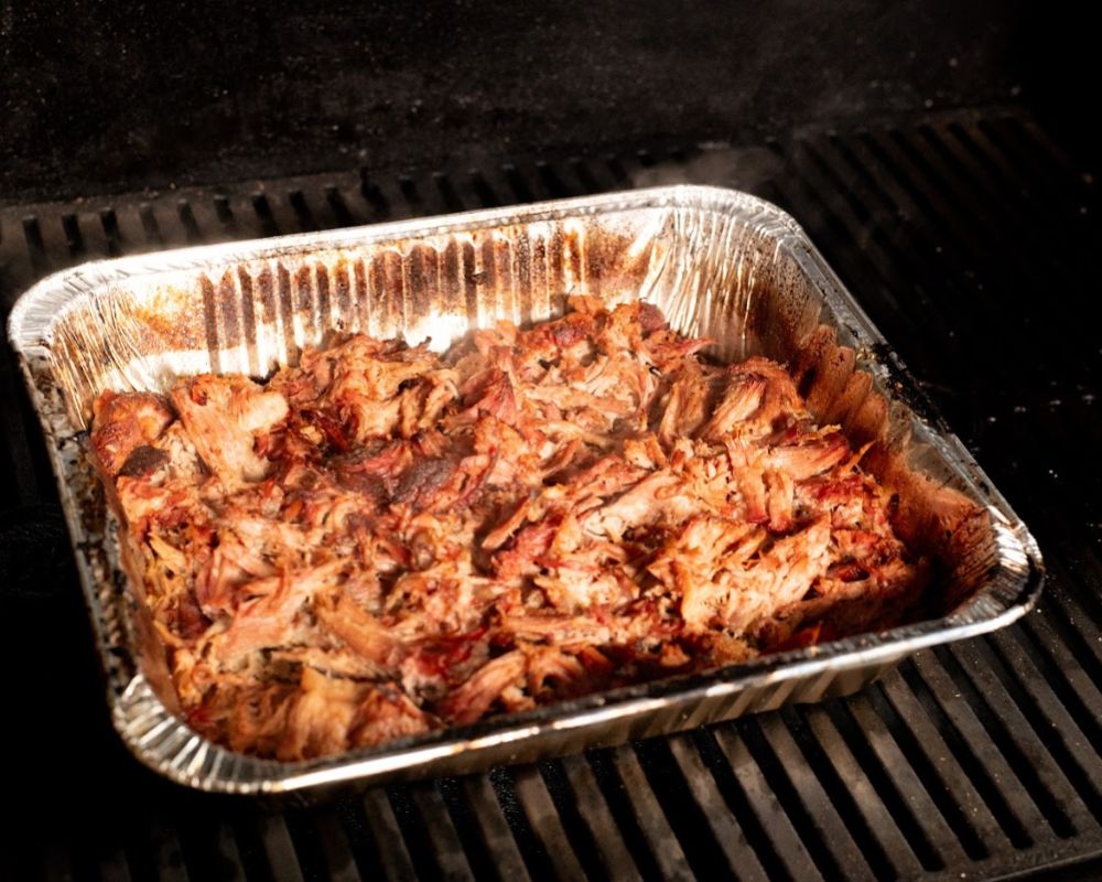 Tray of shredded pulled pork placed back on the Masterbuilt Gravity Feed Smoker for extra crispiness.