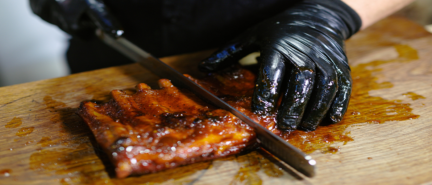 This image shows a man slicing the pork ribs