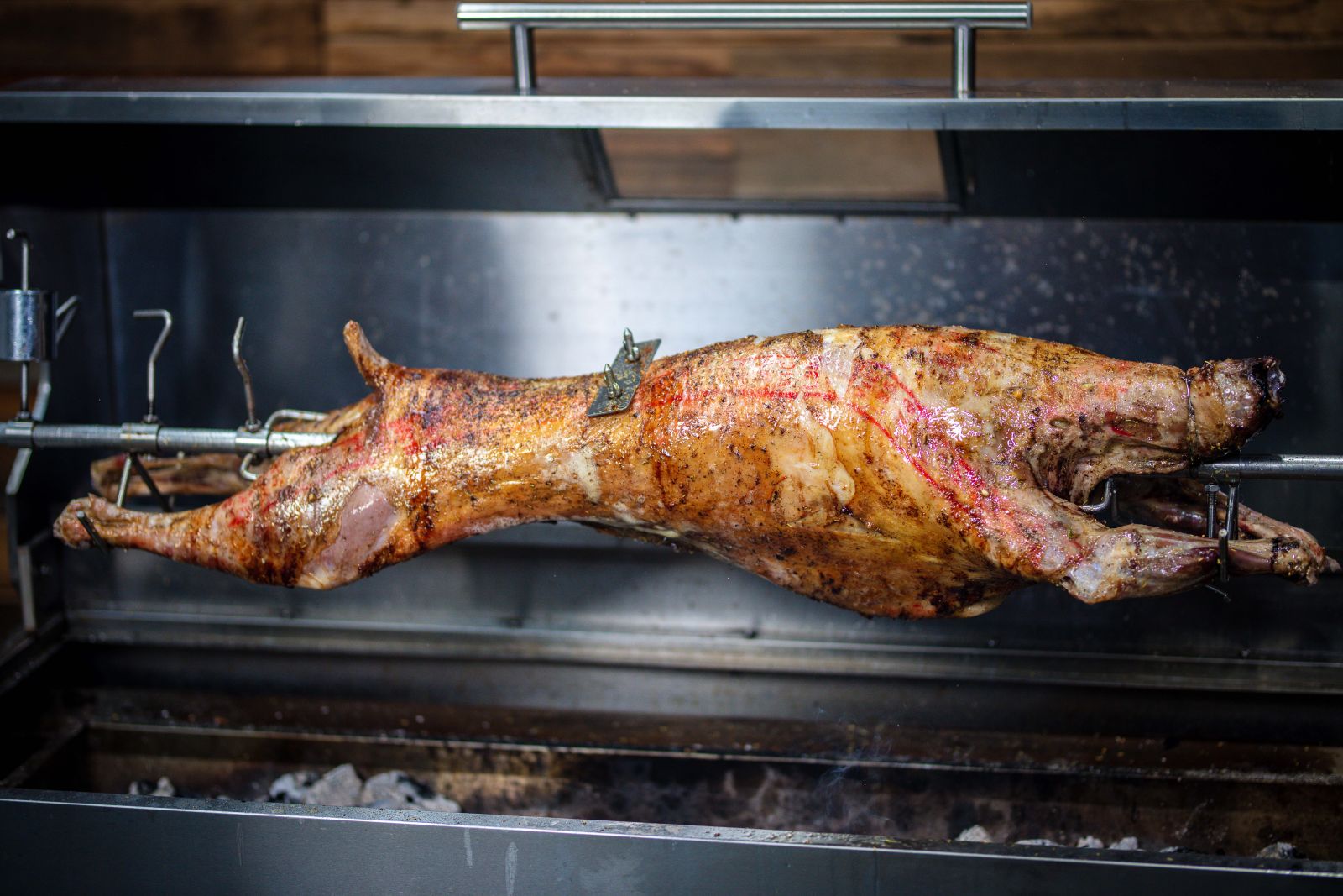 This image shows a whole lamb being cooked in a spit rotisserie.