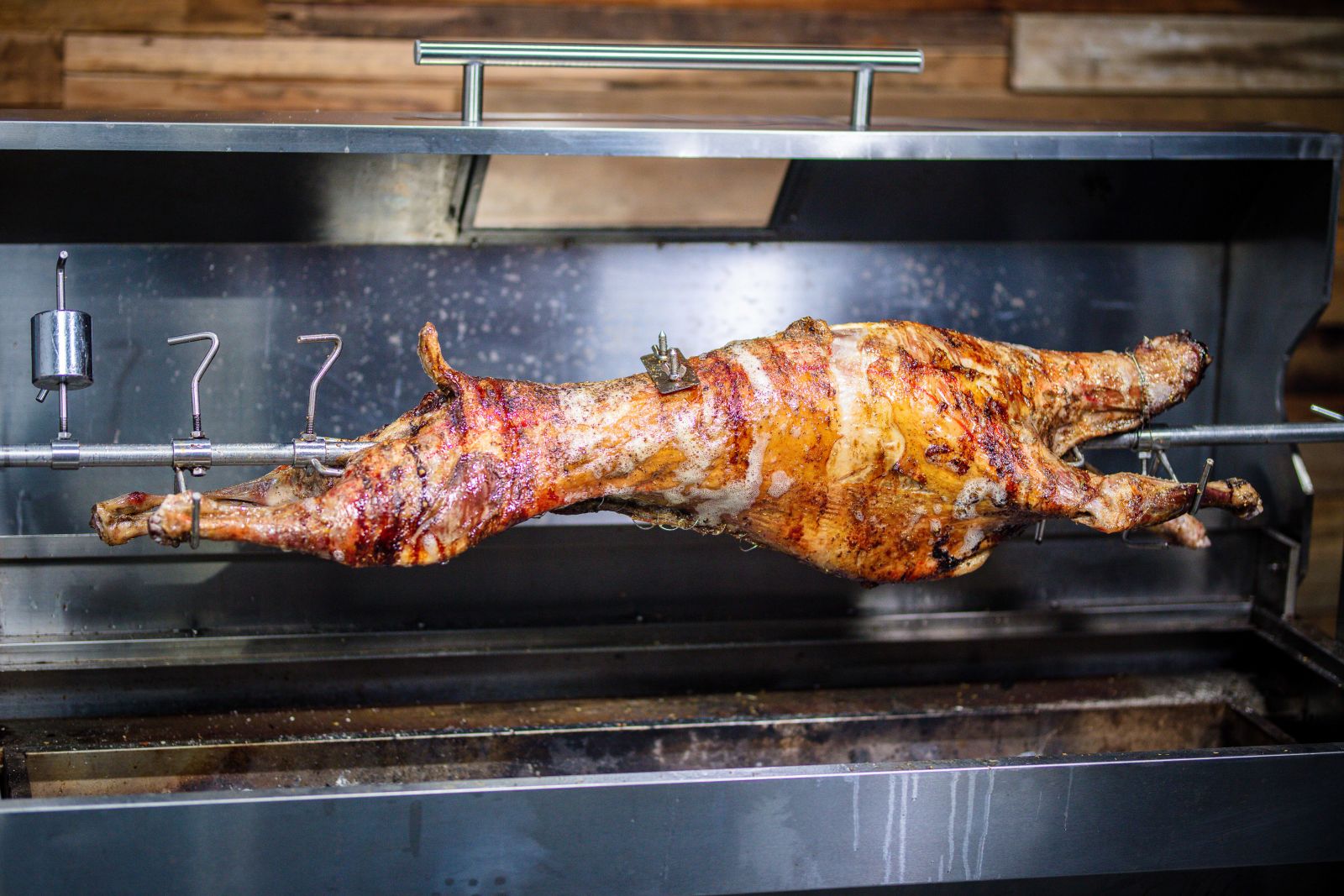 Whole lamb on spit roaster Australia – golden brown roast lamb cooking on rotisserie BBQ