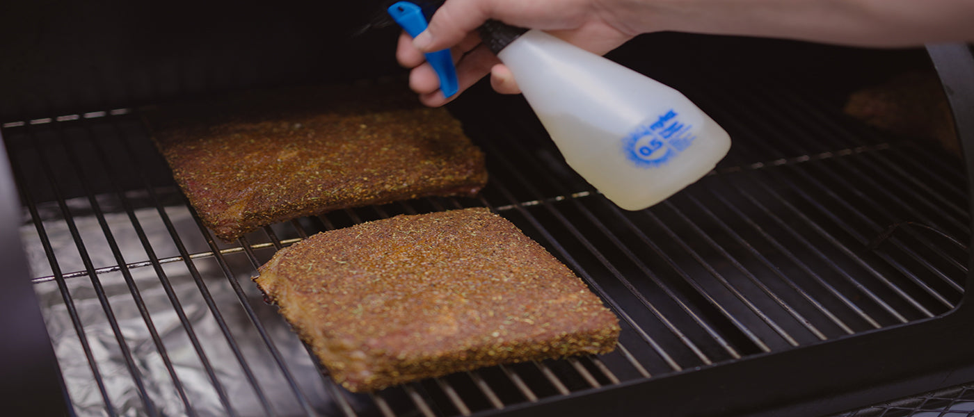 This image shows a man spritzs some apple juice to beef short rib