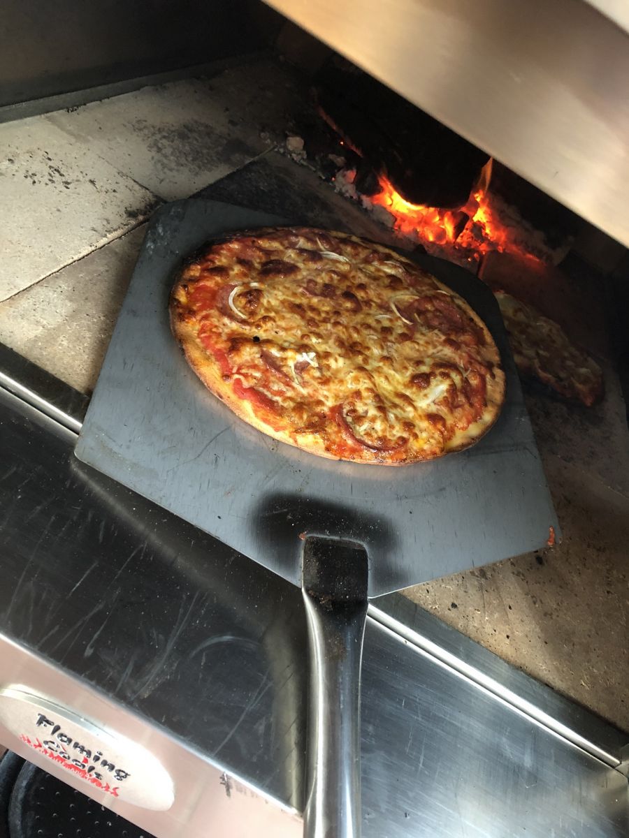 This is a picture of the stainless steel pizza peel removing a pizza from a wood fired pizza oven