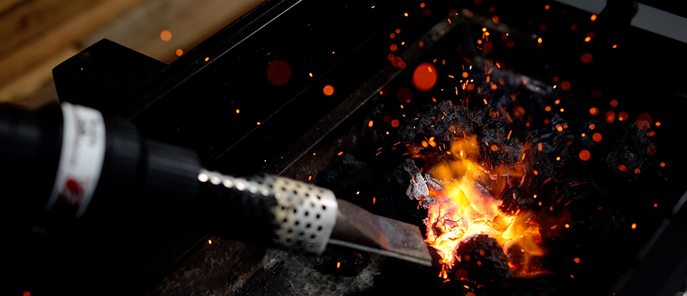 This image shows starting a fire to charcoal using charcoal starter wand