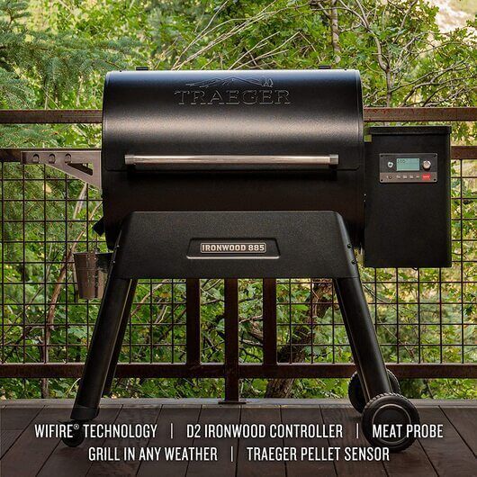 Traeger Ironwood 885 Pellet Grill in black, displayed outdoors on a wooden deck with trees in the background. Grill features WiFIRE technology, D2 Ironwood controller, meat probe, and pellet sensor.