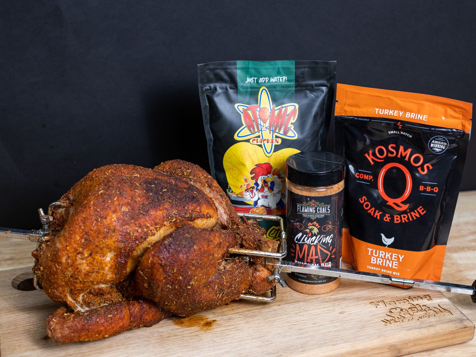 This image shows a whole chicken, Flaming coals clucking mad, Atomic Chicken Stuffing and Kosmos Q Brine. 