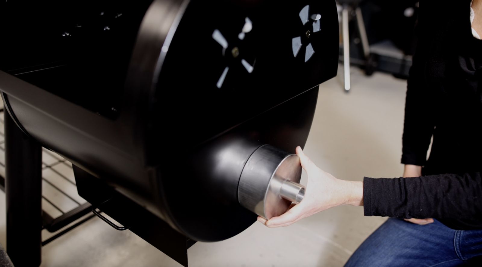 This image shows a woman attaching the Universal adaptor on the offset smoker