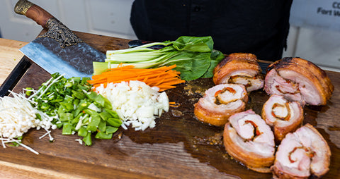 This image shows shows different kinds of sliced vegetables and cooked pork loin