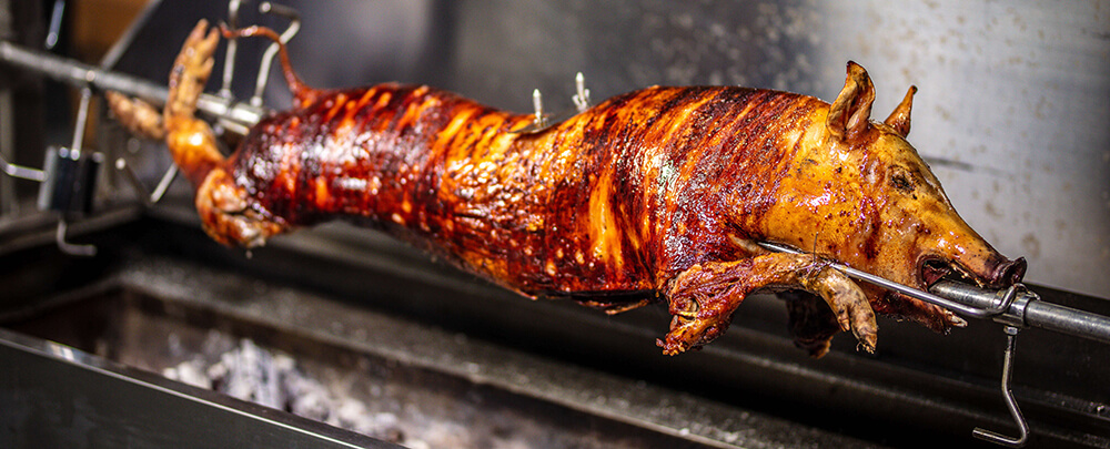 This image shows whole pig cooked in a Spit Rotisserie