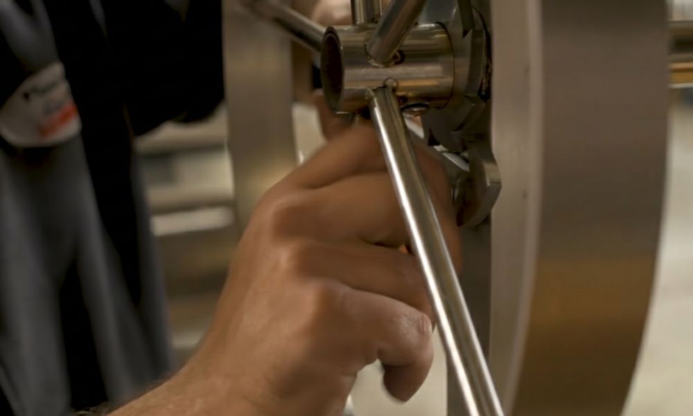 Close-up of a technician tightening the handle spokes on the Stainless Steel Parrilla Argentina Grill’s wheel