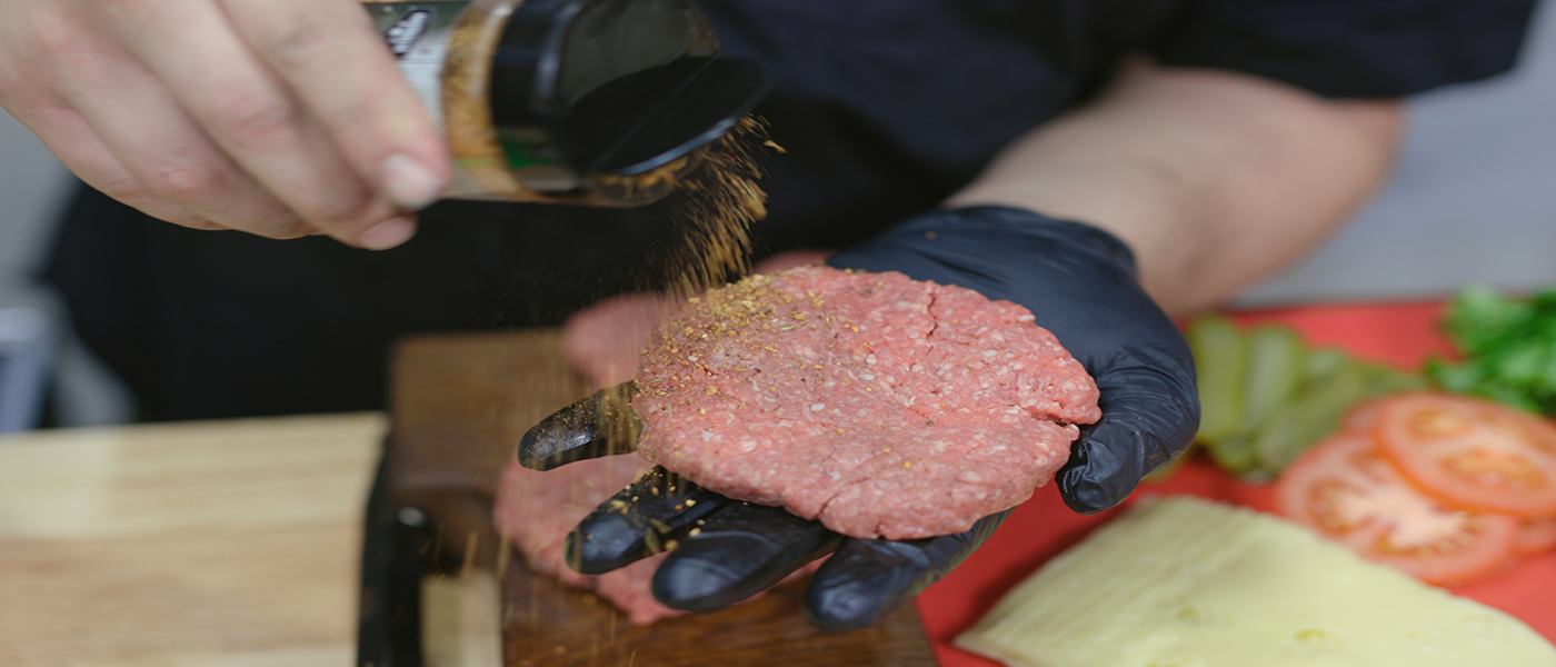 This image shows a man seasoning the beef fatty with Slow Burner Bbq booster Rub