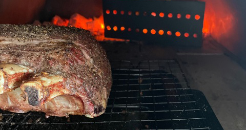This image shows a beef rib roast on wood fired pizza oven