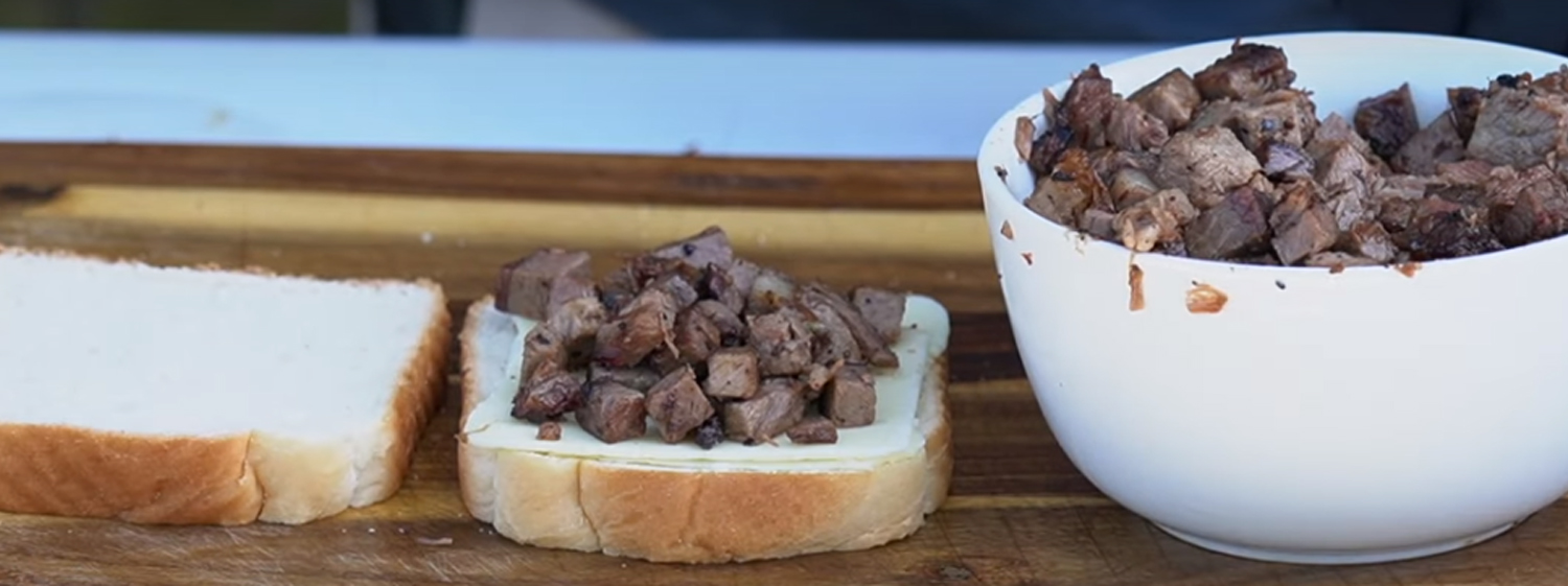 This images shows two pieces of bread with cheese and chopped brisket