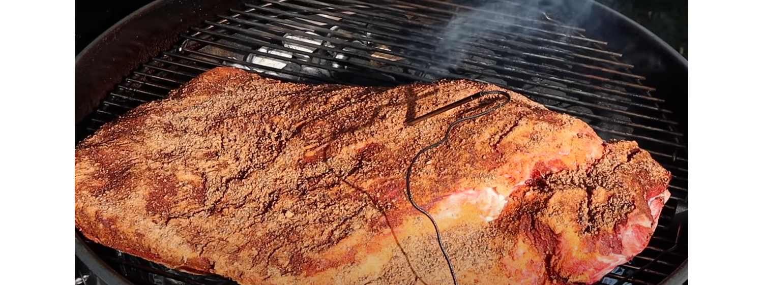 This image shows a brisket placed on the opposite side of the heat on SNS Kettle