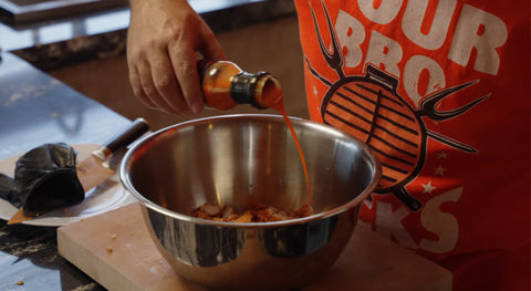 This image shows the fried chickens being seasoned with Kosmos Q Wing sauce