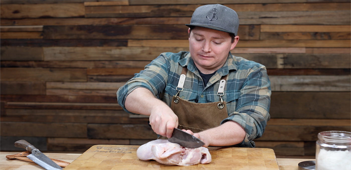 This image shows a man breaking the back of chicken. 