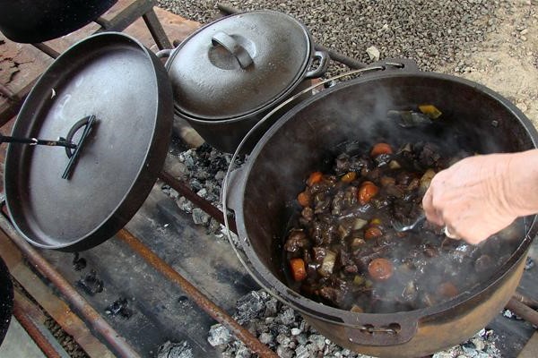 This is a Picture of a cast oven oven being used to cook a stew oven hot coals