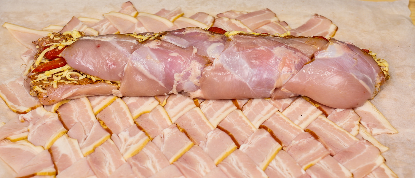 This image shows chicken thighs placed on the top of weaved bacon