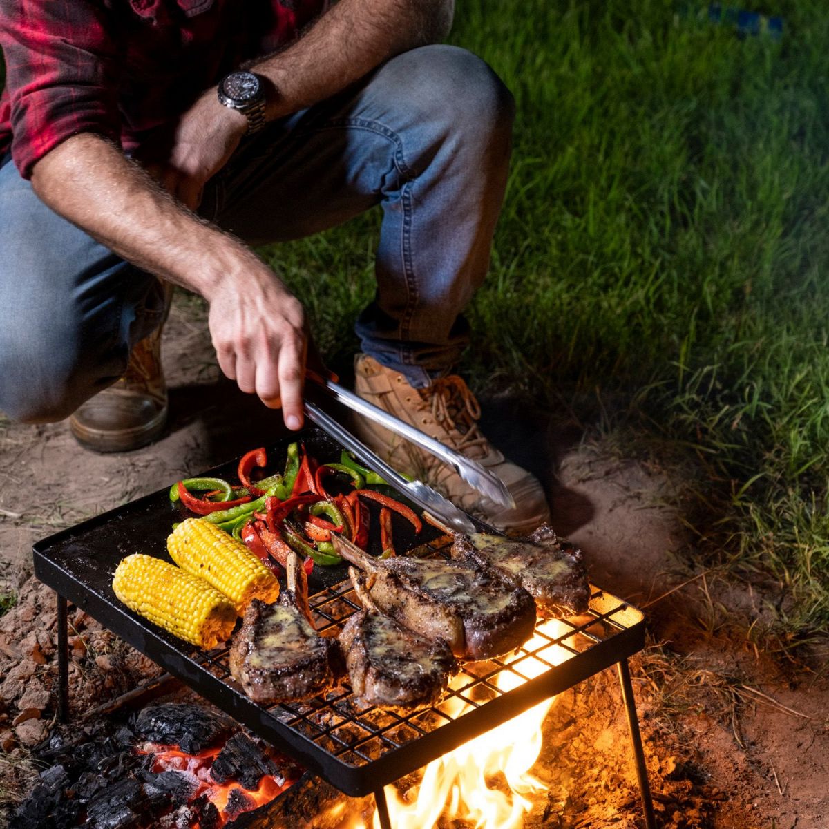 This image shows a man cooking on a Portable Folding Camp Grill and Hotplate