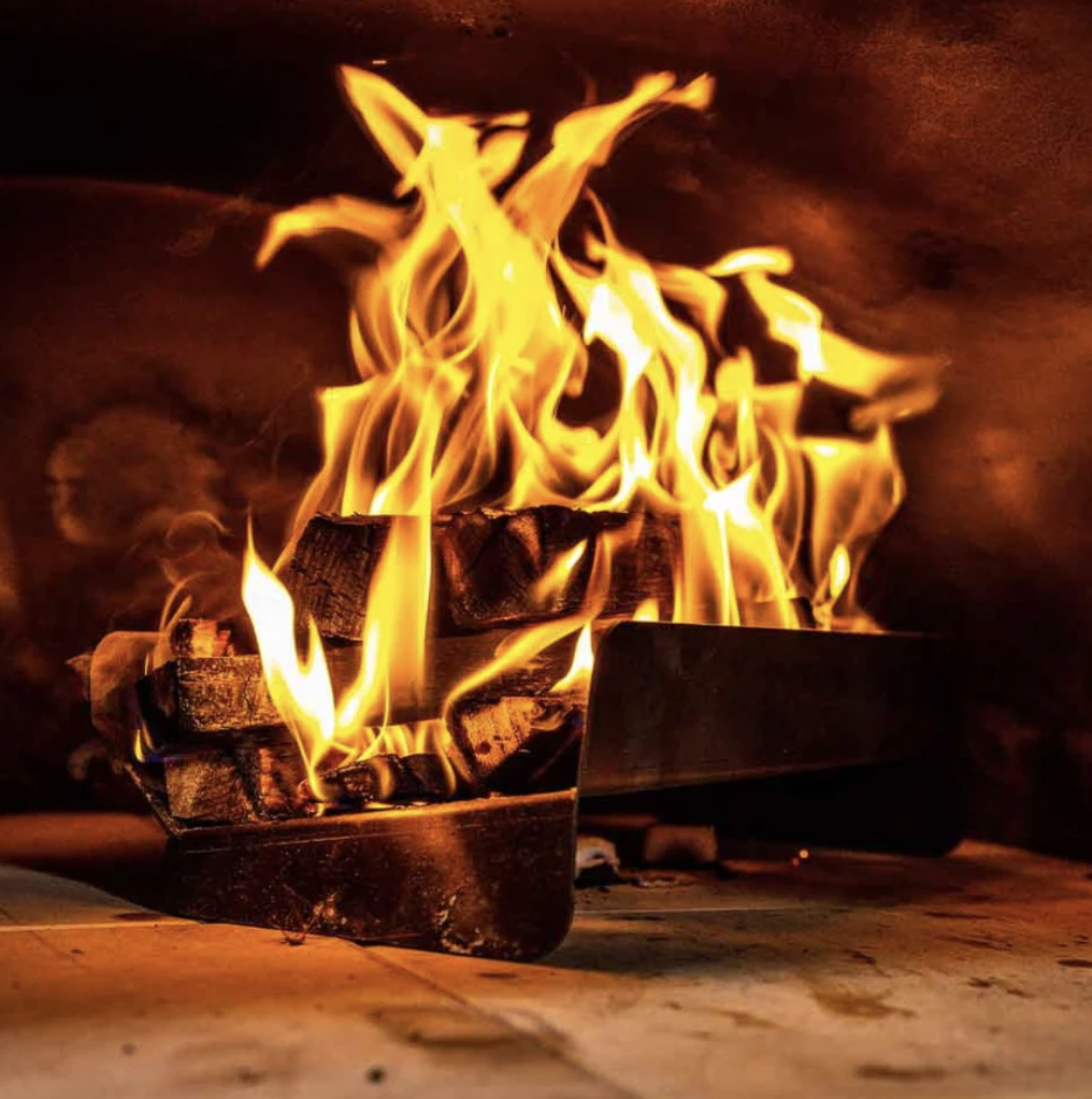 Raised wood holder with lit kindling