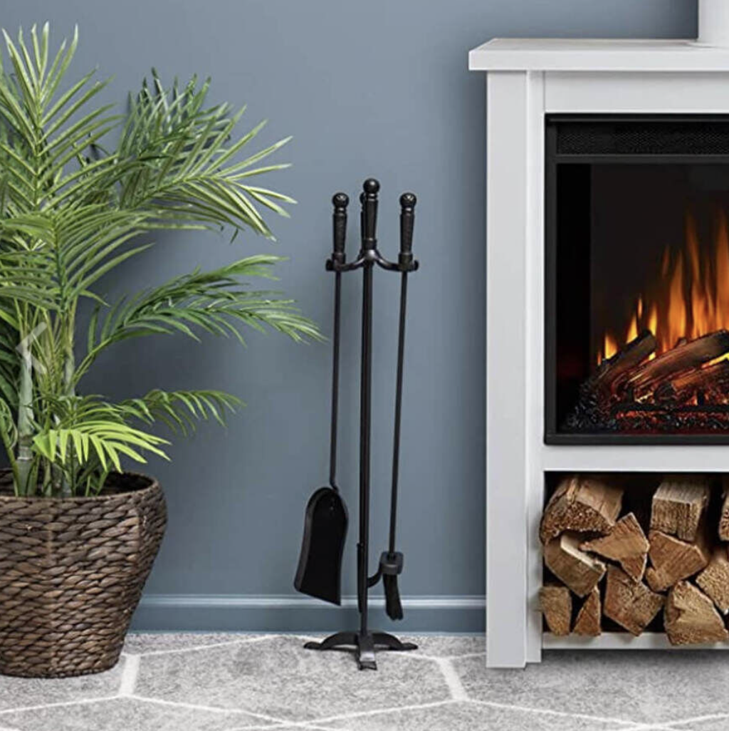 A Black Finish Fire Tool Set - 3 Piece plus Stand positioned next to a fireplace.