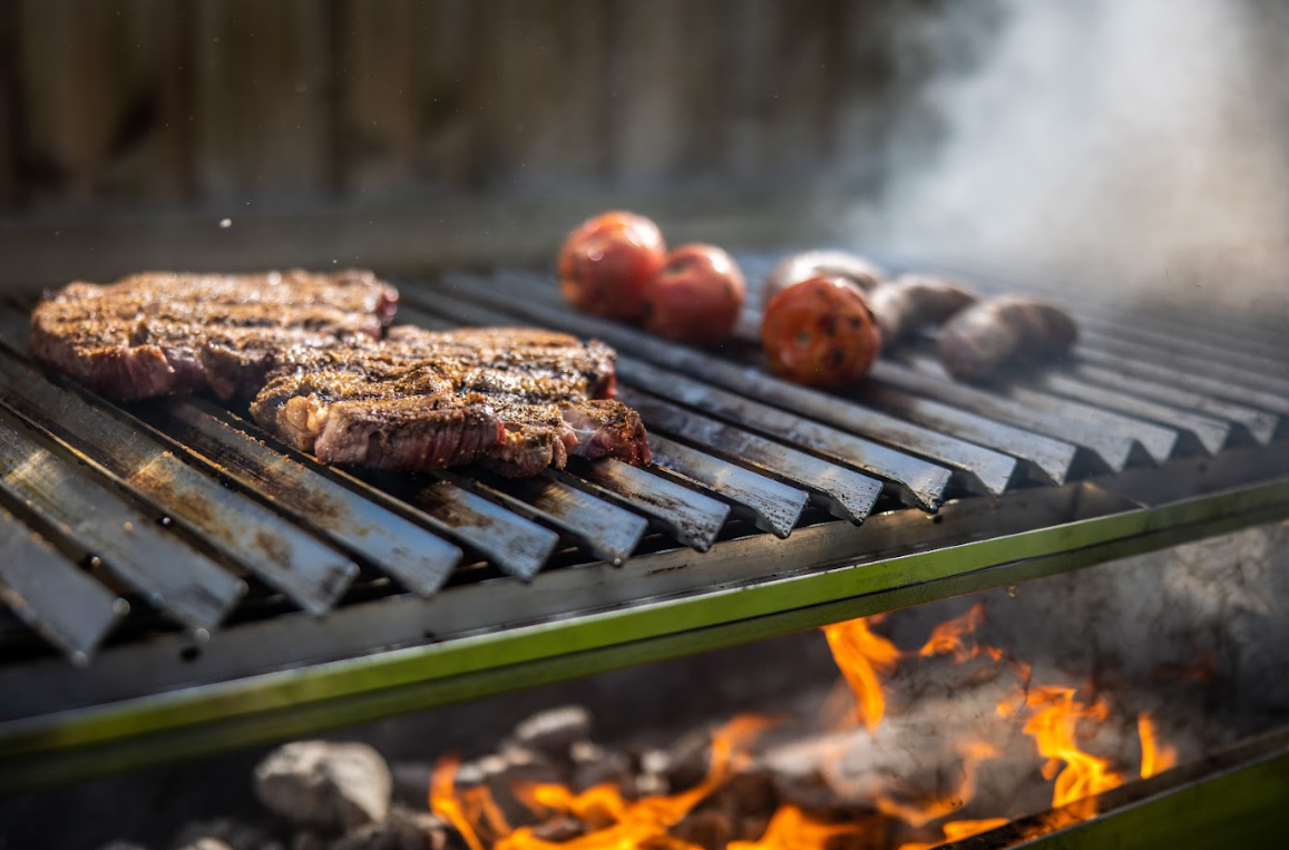 Argentinian style parrilla grill searing steaks over hot coals