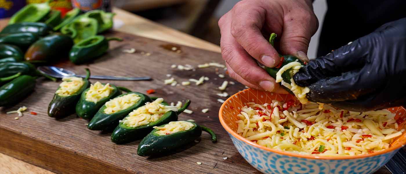 This image shows a man adding mozarella cheese to jalapeñop poppers. 