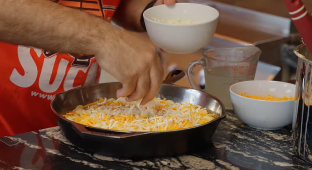 This image shows the macaroni pasta being layered in the cast iron pan