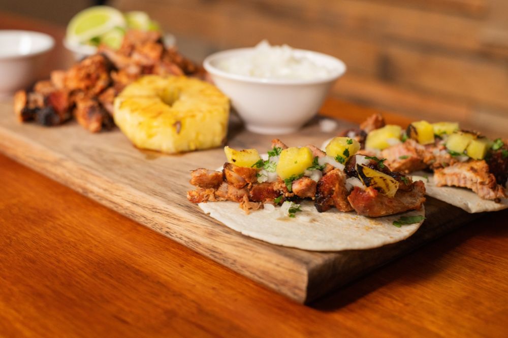 Authentic Mexican Taco Al Pastor with juicy spit-roasted pork, pineapple, onion, and fresh coriander, served on warm tortillas.