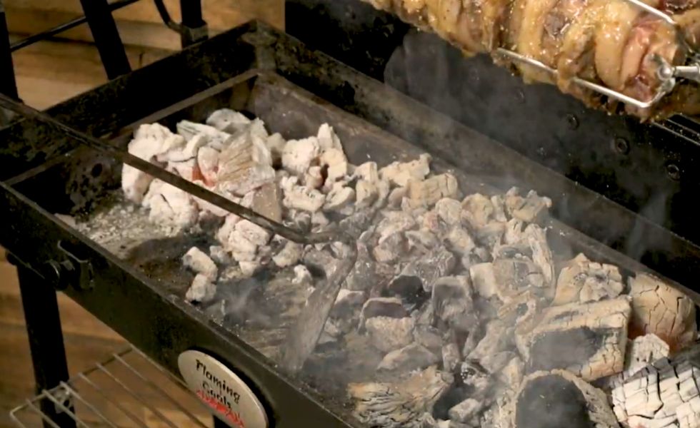 This_images_shows_charcoal_rake_being_used_to_move the_coals