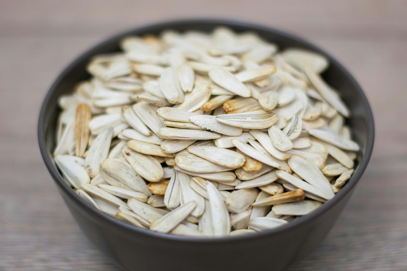A close-up image of a bowl filled with roasted pumpkin seeds, showing their natural light color and smooth texture.