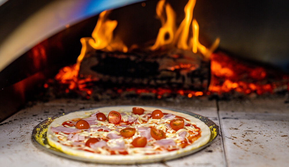 This image shows pizza cooked on wood fired pizza oven