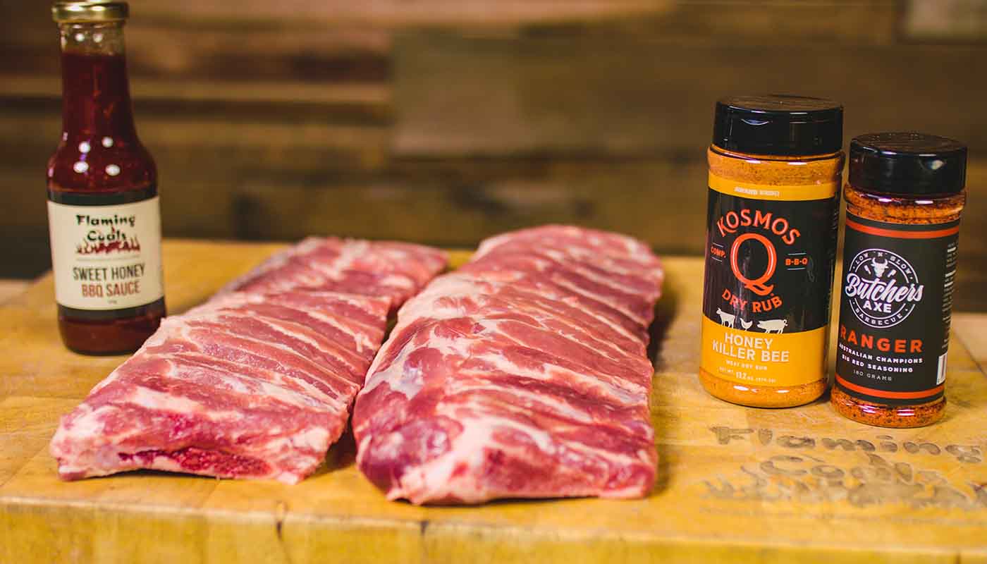 This image shows two chunks of pork rib, Flaming coals sweet honey sauce, Kosmos Q honey Killer bee and Butcher Rub Ranger