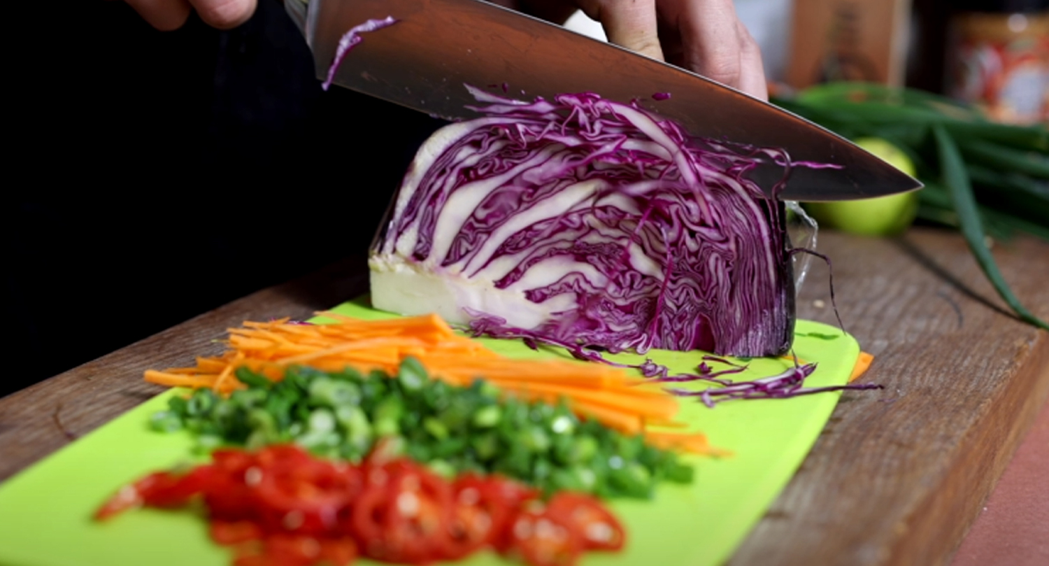 This image shows a sliced carrots, chili, onions leaves and cabbage