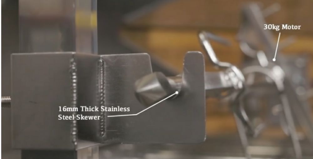 Close-up of stainless steel hooded rotisserie and Cyprus grill showing 16mm thick skewer and 30kg motor connection.