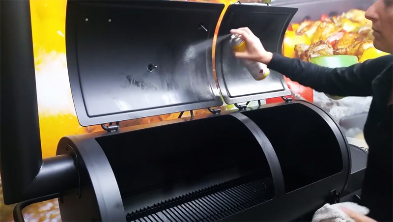 This image shows oil being sprayed in the offset smoker during the seasoning process