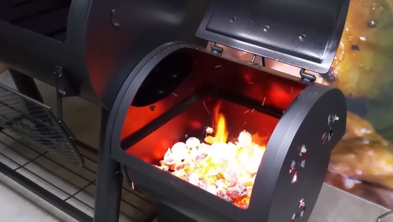 This picture shows the firebox in an offset smoker full of coals during the seasoning process. 