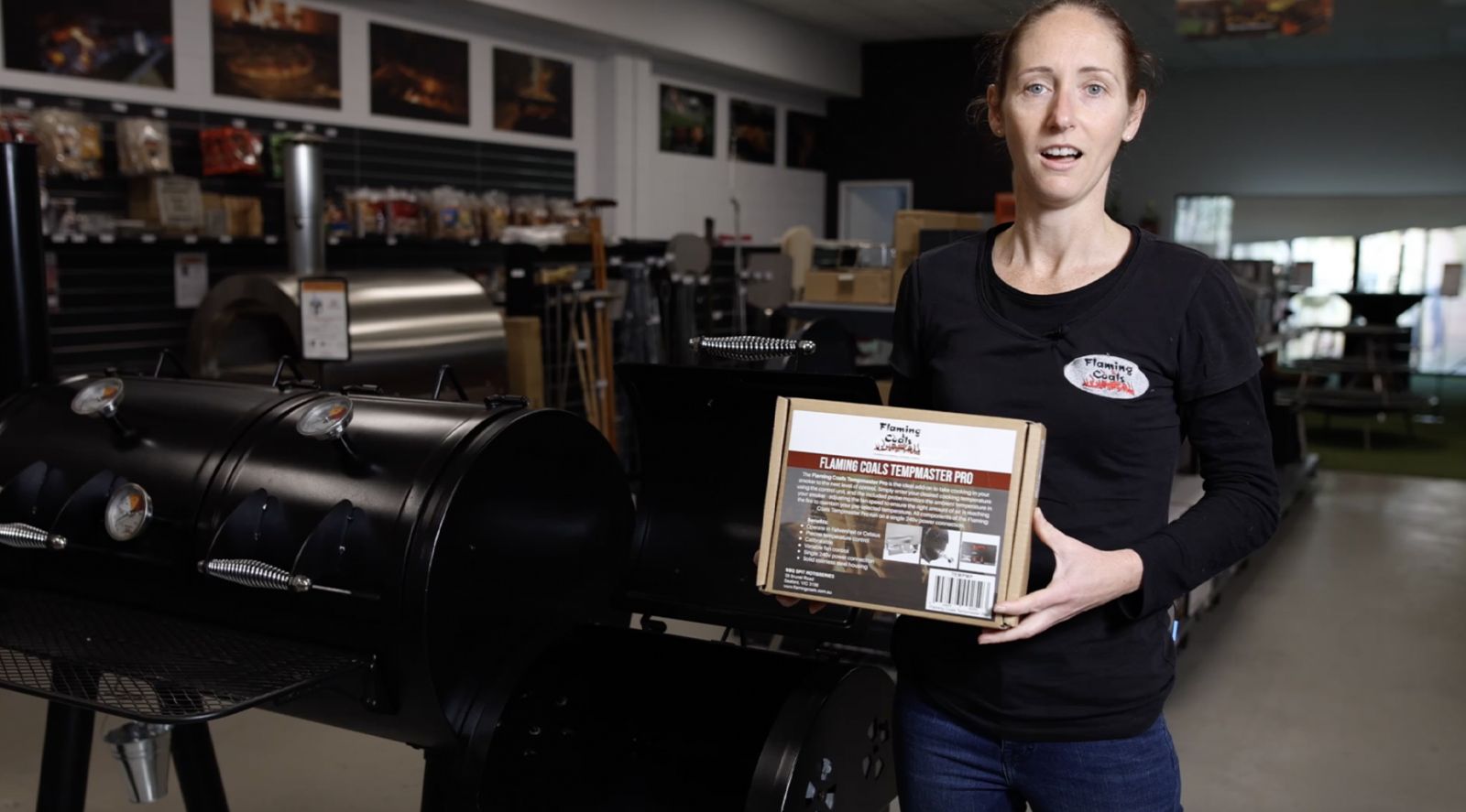 This image shows an offset smoker and a woman holding the Tempmaster pro 