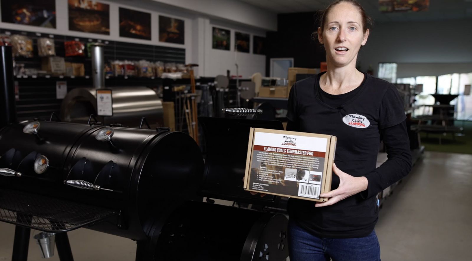 This image shows an offset smoker and a woman holding the Tempmaster pro 
