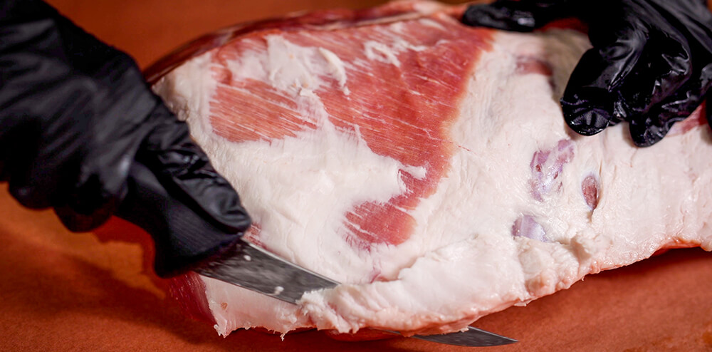 This image shows the excess fat of the pork being trimmed
